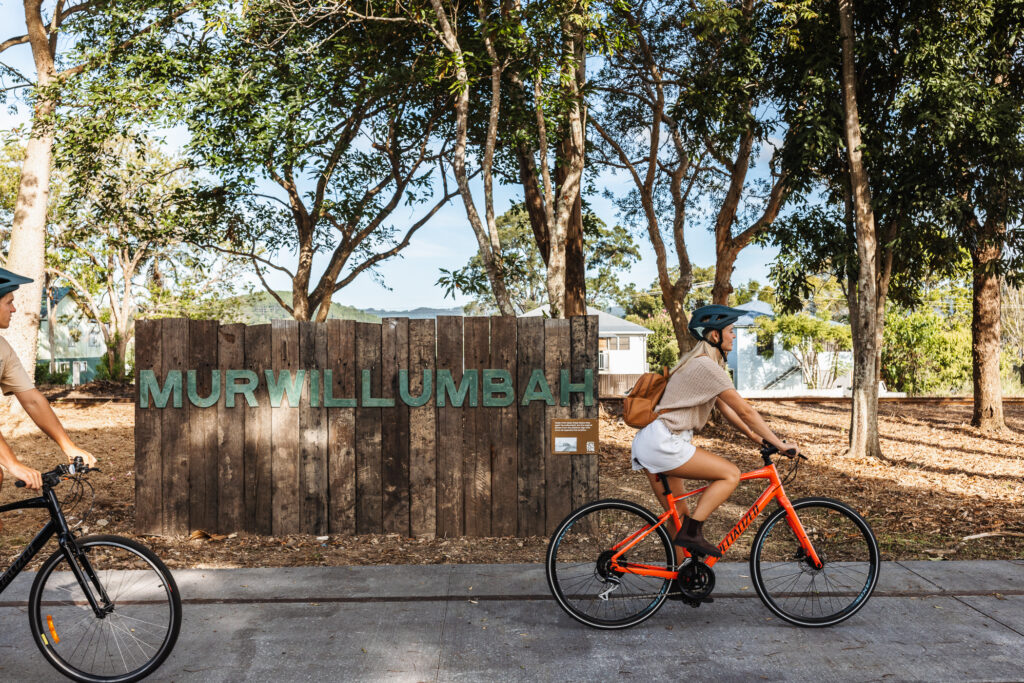 girl riding bike past murwillumbah sign