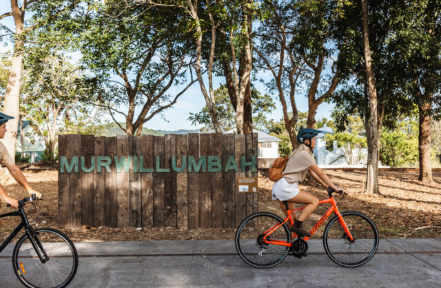 girl riding bike past murwillumbah sign