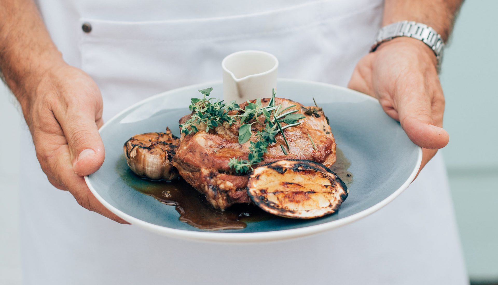 Woman carrying a plate of delicious eggplant dish - Experience amazing culinary delights in Tweed, NSW.