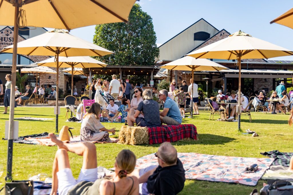 people sitting on the lawn of husk farm distillery enjoying the sun