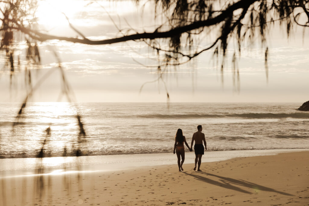 couple walking along cabarita beach hand in hand enjoying a warm winter escape in The Tweed