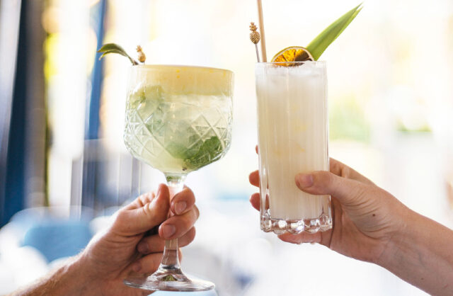 one cocktail with passionfruit foam and one pina colada cocktail in tall glass