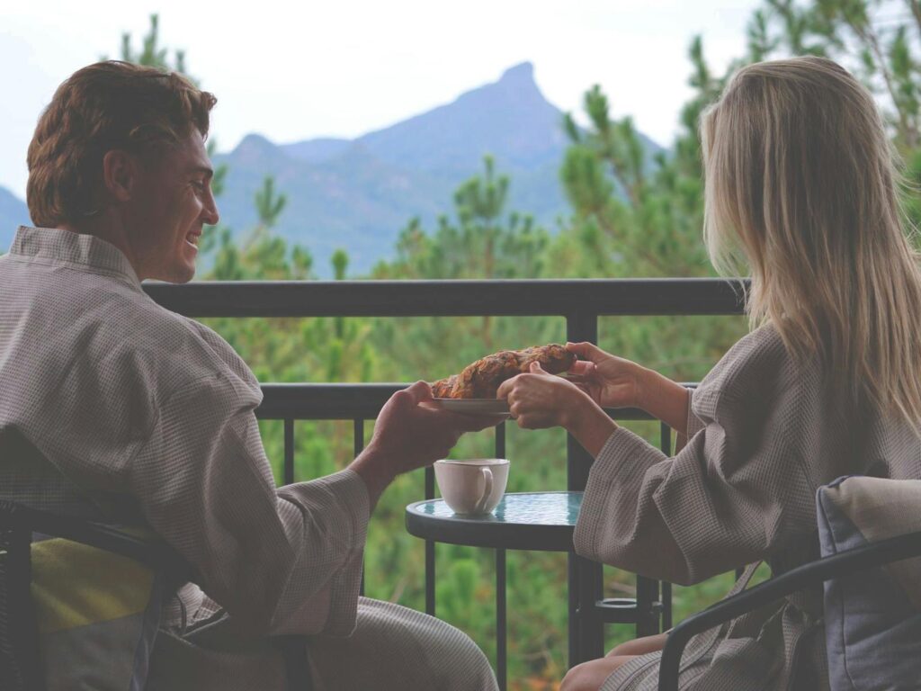 couple enjoy coffee on balcony with wollumbin mount warning in background