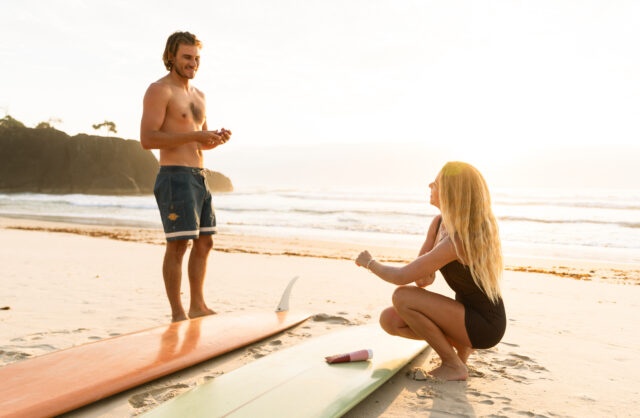 Couple apply we are feel good inc sunscreen on beach